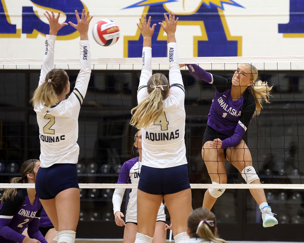 Onalaska's Makena McGarry drives an attack through the Aquinas block of Ava Kujak and Abby Ziolkowski during the third set of Tuesday's Mississippi Valley Conference opener. -- PHOTO BY NATE BEIER/GX3 MEDIA