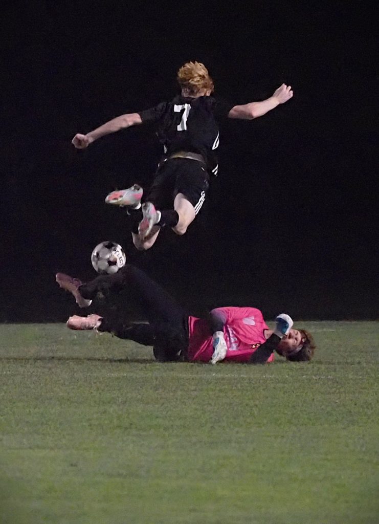 Drake Wonderling (7) is sent airborne by Logan's GK Parker Stevermer while stopping the shot -- TARA WALTERS PHOTO.