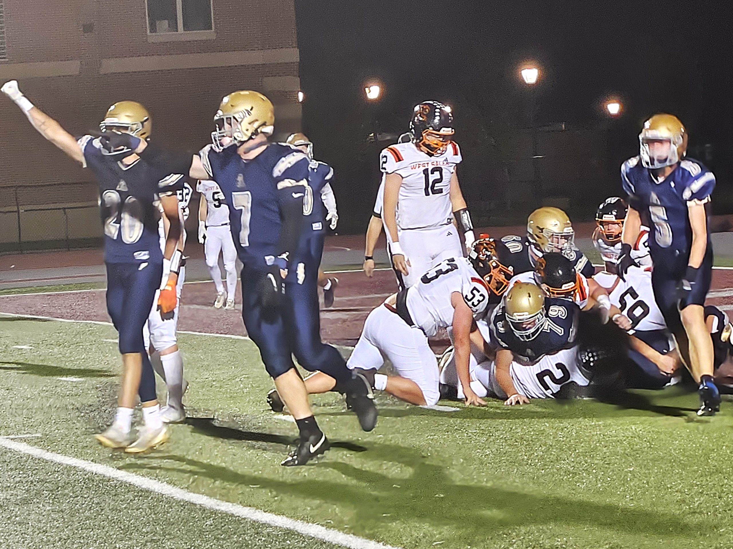 The Aquinas football team celebrates a fourth-down stop at the goal line during Friday's 20-13 win over West Salem. -- TODD SOMMERFELDT PHOTO