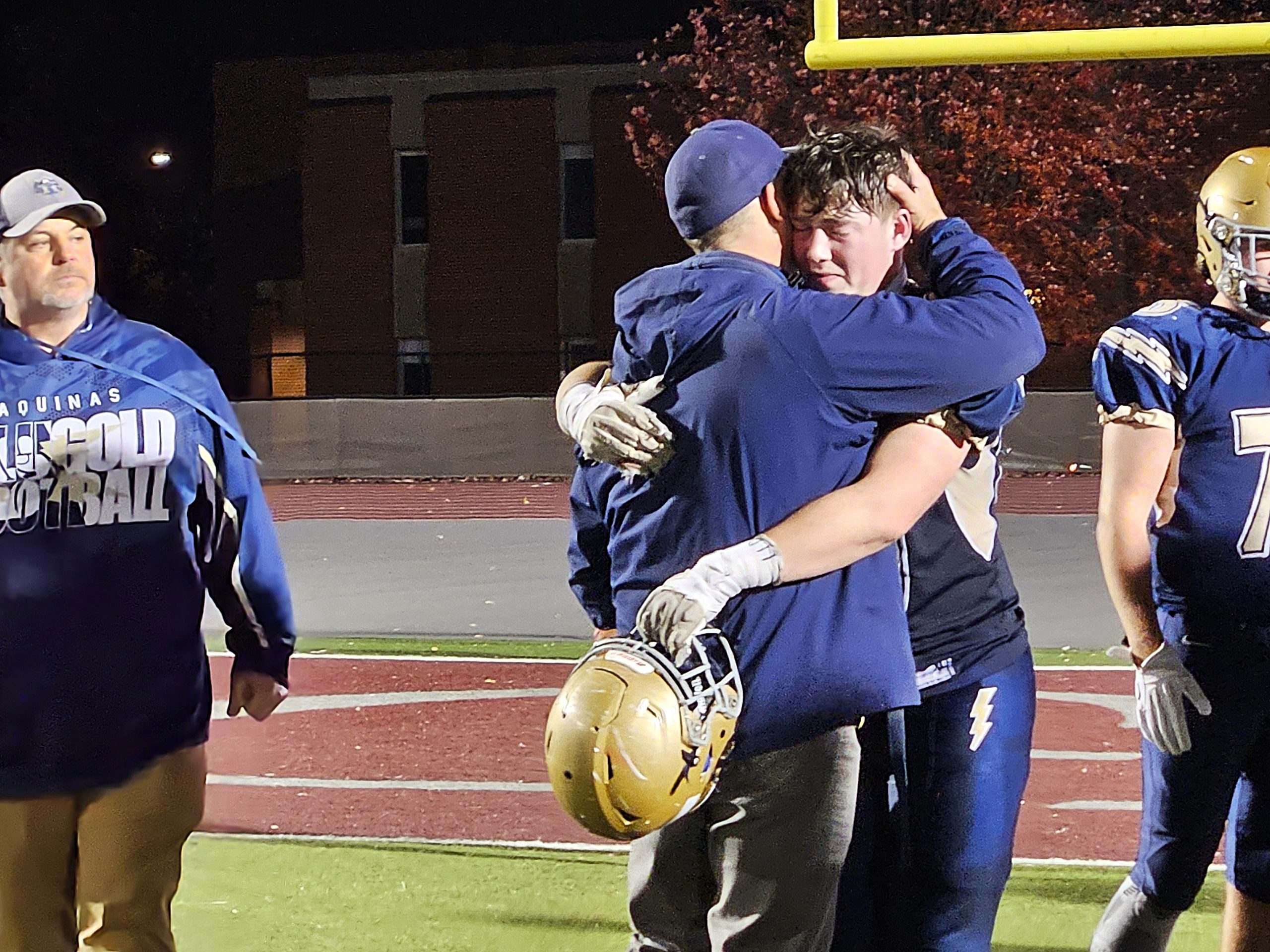 Aquinas football coach Tom Lee hugs senior Will Flottmeyer after a 27-20 loss to Baldwin-Woodville in the WIAA Division 4 playoffs on Friday. -- TODD SOMMERFELDT PHOTO