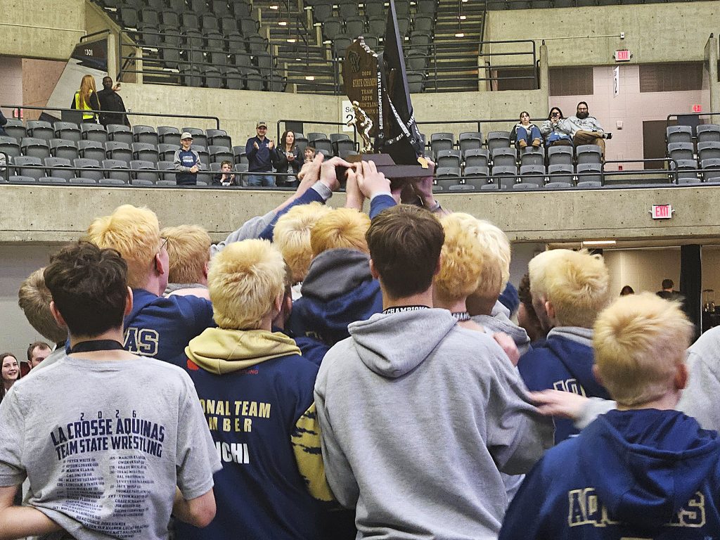 The Aquinas wrestling team holds its WIAA Division 3 championship trophy in the air at the La Crosse Center. -- TODD SOMMERFELDT PHOTO